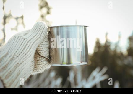 La main dans la mitaine permet de tenir une tasse en métal, un gros plan et une mise au point sélective Banque D'Images