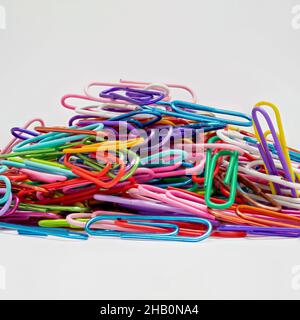 Image macro d'un tas de fixations de grands trombones multicolores sur un fond blanc Banque D'Images