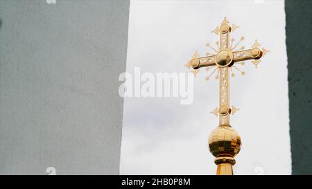 Concept de religion et de foi, vue de dessous d'une croix dorée de l'église.Vidéo.Grande croix dorée sur fond ciel nuageux Banque D'Images