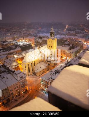 Magnifique paysage urbain d'hiver Lviv avec des toits couverts de neige du sommet de l'hôtel de ville, Ukraine, Europe.Cathédrale latine illuminée par les lumières de la ville.Photographie de paysage Banque D'Images
