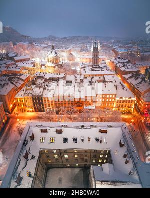 Magnifique paysage urbain d'hiver ville de Lviv illuminée par les lumières de la ville avec des toits couverts de neige du sommet de l'hôtel de ville, Ukraine, Europe.Photographie de paysage Banque D'Images
