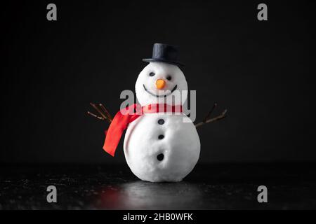 Bonhomme de neige drôle dans un chapeau élégant et rouge scalf sur fond noir.Prise de vue en studio Banque D'Images
