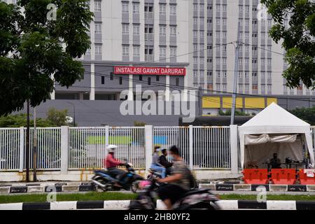 Jakarta, Jakarta.16th décembre 2021.Les personnes portant un masque passent devant l'hôpital d'urgence Wisma Atlet, un hôpital pour les patients COVID-19, à Jakarta, Indonésie, le 16 décembre 2021.L'Indonésie a détecté son premier cas de variante d'Omicron dans un employé du service de nettoyage dans un hôpital pour les patients de COVID-19 dans la capitale Jakarta, a déclaré jeudi le ministre de la Santé Budi Gunadi Sadikin.Credit: Xu Qin/Xinhua/Alamy Live News Banque D'Images