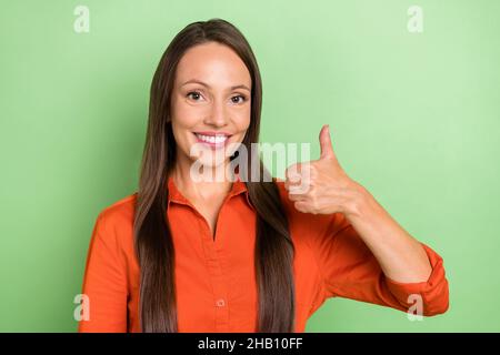 Photo de jeune femme charmante montrer la publicité de pouce vers le haut bon promoteur isolé sur fond vert couleur Banque D'Images