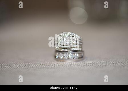 anneaux de mariage en or blanc avec diamants empilés sur une surface blanche et bokeh Banque D'Images