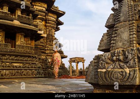 Belur, Karnataka, Inde : Temple Chennakhava du 12th siècle.Une femme marche sur la plate-forme jagati pour la cirambulation (pradakshina-patha) autour de la Banque D'Images