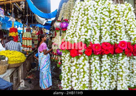 Mysore, Karnataka, Inde : Une femme fait des magasins de guirlandes de fleurs au marché de Devaraja. Banque D'Images