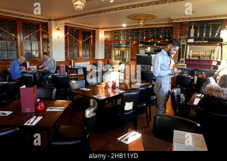 Un serveur prend les commandes de deux clients dans le restaurant quasi vide Cassia Sambuca à North Shields, North Tyneside, qui serait normalement emballé avec des clients profitant des offres spéciales du déjeuner.Les entreprises d'accueil augmentent les demandes de soutien du gouvernement pour des pubs et des restaurants à succès tandis que la variante d'Omicron balaie le pays et que la confiance des consommateurs est ébranlées par de nouvelles restrictions et des avertissements sanitaires croissants.Date de la photo: Jeudi 16 décembre 2021. Banque D'Images