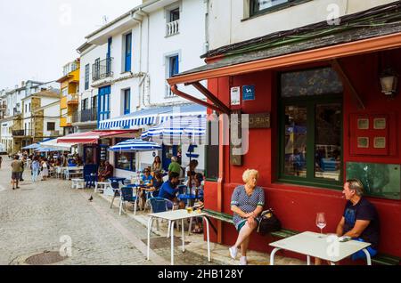 Tapia de Casariego, Asturies, Espagne : Un homme et une femme bavarde dans un café en plein air dans le port de pêche. Banque D'Images