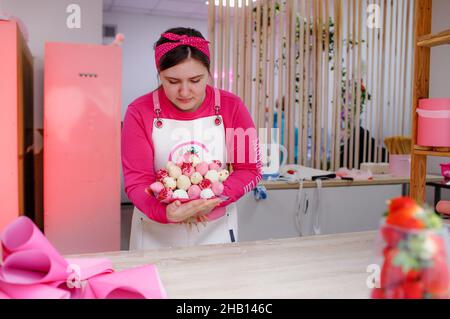 une petite pâtissière recueille un beau bouquet de fraises enrobées de chocolat. Banque D'Images