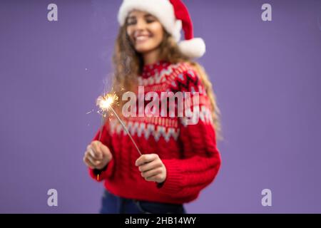 Mise au point sélective.Happy Santa fille tient des spameuses brûlantes dans le studio tourné sur fond violet Banque D'Images