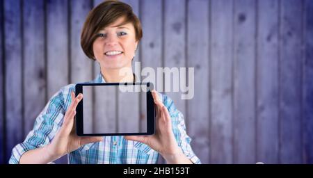 Image composite d'une femme caucasienne tenant une tablette numérique sur fond de bois bleu Banque D'Images