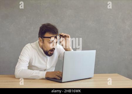 Un jeune homme surpris de gagner de l'argent en ligne regardant l'écran d'ordinateur portable Banque D'Images