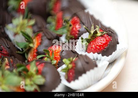 De délicieuses baies enrobées de chocolat sur un plat blanc au bar du désert Banque D'Images