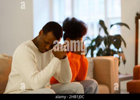 Triste couple noir pensif après le combat assis sur le canapé offensé penser à la crise de relation ou de conflit Banque D'Images