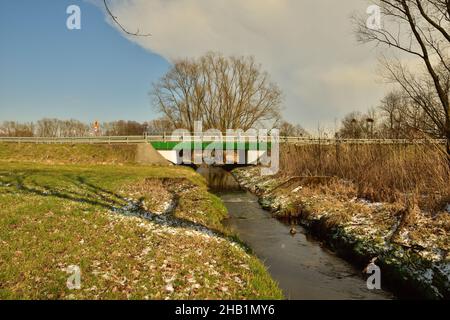 Un pont qui relie les deux banques sur un petit ruisseau un jour de printemps frais.Eau. Banque D'Images