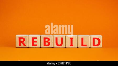 Reconstruire et construire le symbole.Le mot concept reconstruire sur des cubes en bois.Belle table orange, fond orange, espace de copie.Reconstruction et construction de l'entreprise Banque D'Images