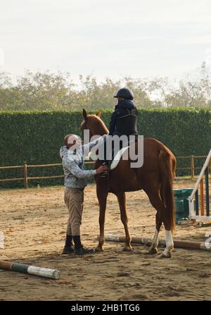 Entraîneur enseignant le cheval de cheval d'enfant avec des obstacles. Banque D'Images