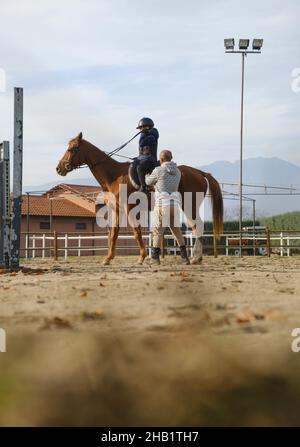 Entraîneur enseignant le cheval de cheval d'enfant avec des obstacles. Banque D'Images