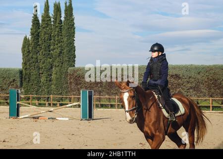 Jeune garçon à cheval au ranch avec des obstacles. Banque D'Images