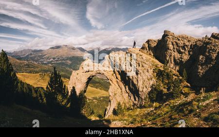 Un homme heureux au-dessus d'une formation de roche d'arche contre les hautes montagnes.Pyrénées. Banque D'Images