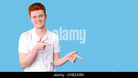 Jeune homme beau portant un t-shirt blanc décontracté souriant heureux pointant avec ses pouces et d'indiquer les doigts à l'espace de copie sur fond bleu. Banque D'Images