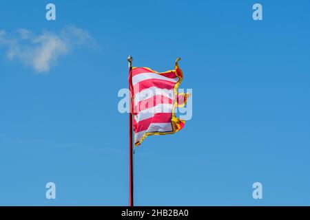 Drapeau coloré éclatant soufflant dans le vent en plein soleil vers ciel bleu clair dans une journée ensoleillée près du château de Buda à Budapest, Hongrie Banque D'Images