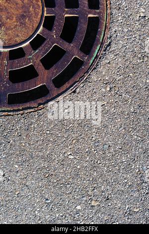 Trappe d'égout ronde avec grille sur une route en asphalte.Vue de dessus Banque D'Images