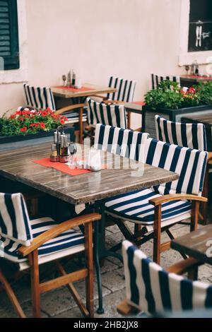 Chaises avec capes rayées sur des tables en bois dans un petit café confortable Banque D'Images