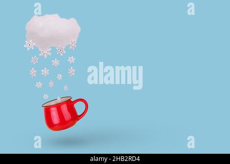 Concept créatif avec nuage, flocon de neige tombant en hiver et mug sur fond bleu pastel.Concept de vacances d'hiver minimales. Banque D'Images