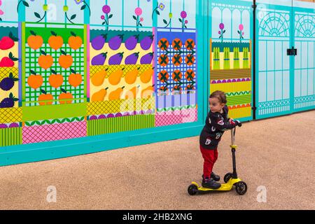 Jeune enfant en scooter à Merchants Way, une nouvelle route de randonnée dynamique à travers le New Covent Garden Market vers le bord de la rivière à Nine Elms, Londres, Royaume-Uni Banque D'Images