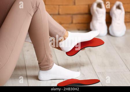 Femme sportive qui s'attache à la semelle intérieure orthopédique rouge à la maison Banque D'Images