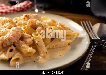 Un gros plan d'une pâte sèche de penne rigate avec une délicieuse crème de crevettes. Banque D'Images