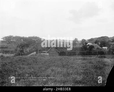 Lointaine View Womens prison, Isle of Pines, Nouméa, Burton Brothers studio, studio de photographie,1899, Dunedin, photographie en noir et blanc, d'élévation au-dessus de la colonie, avec des toits de chaume et une clôture en bois et en chaume.De grands arbres tropicaux y compris des cocotiers et à distance sur la colline au-dessus des bâtiments coloniaux y compris une église avec la flèche Banque D'Images