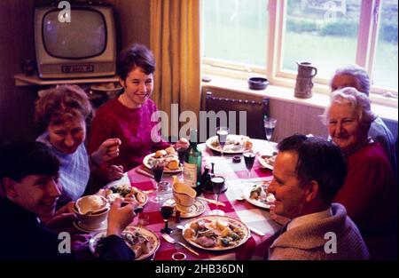 Repas de Noël familial traditionnel tout assis autour de table manger et boire, c 1960, Angleterre, Royaume-Uni Banque D'Images