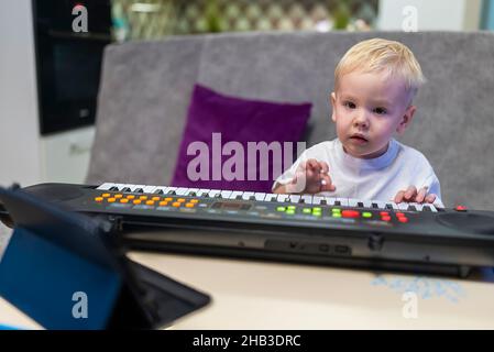 petit garçon apprenant à jouer du piano à la maison Banque D'Images