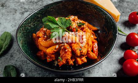 Gros plan de pâtes de penne dans une sauce tomate ornée de feuilles de coriandre Banque D'Images