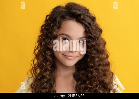 enfant souriant avec de longs cheveux bouclés et une peau parfaite, frisée Banque D'Images