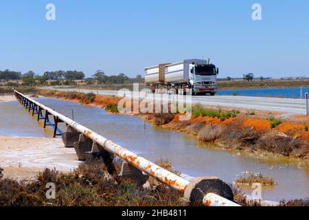 Conduite d'eau de fond sur des peuplements traversant le lac salé avec un camion de passage, Wongan Hills, Australie occidentale Banque D'Images