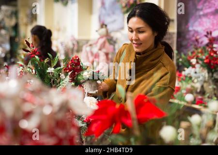 Une femme asiatique positive choisit une composition de Noël Banque D'Images