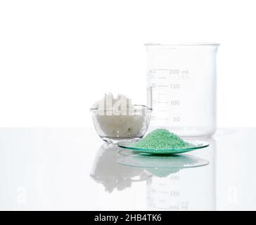 Sulfate ferreux dans le verre de surveillance chimique, placer à côté du sel en flocons et du bécher.Gros plan sur l'ingrédient chimique sur la table de laboratoire blanche.Vue latérale Banque D'Images