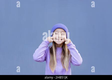 Un enfant qui montre une dent de lait manquée.Changer de concept de dents.Jolie petite fille caucasienne aux cheveux blonds de huit ans sur fond violet avec espace de copie Banque D'Images