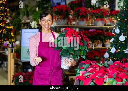 Une fleuriste latino-américaine souriante se dresse avec des fleurs Banque D'Images