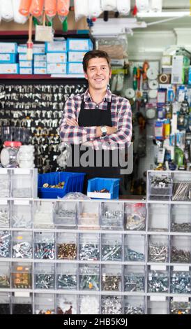 Homme debout près du comptoir et détails de vente pour la plomberie dans l'atelier de quincaillerie Banque D'Images