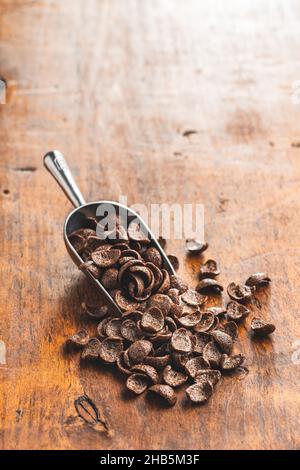 Petit-déjeuner au chocolat sucré, flocons de céréales dans une cuillère sur une table en bois. Banque D'Images