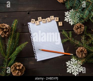 liste de souhaits de noël avec stylo écrit avec des lettres en bois et des décorations de noël sur un espace en bois brun foncé pour le texte Banque D'Images