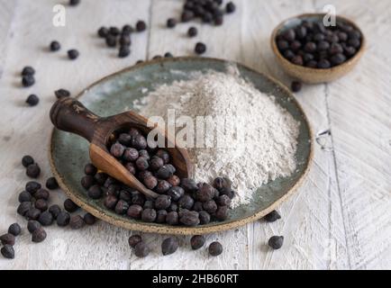 Assiette de farine de pois chiches noirs et de haricots avec une cuillère en bois, à proximité sur une table en bois blanc.Haricots traditionnels d'Apulia et Basilicate en Italie Banque D'Images