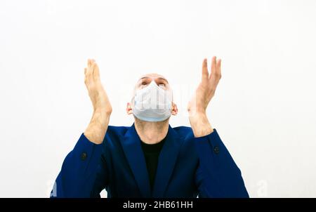 Gros plan sur le visage masculin dans une veste bleue qui se fixe en pointant ses mains vers le haut.Espoir et frustrations dans le concept de quarantaine. Banque D'Images