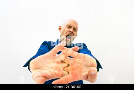 Homme dans des vêtements formels fatigués tient ses mains en avant étirant et avec les yawns de mounth ouverts.Image d'espace vide sur fond blanc.Concept de t Banque D'Images