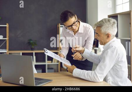 Le client principal signe les documents à l'agent bancaire, au conseiller financier ou au bureau de l'assureur Banque D'Images